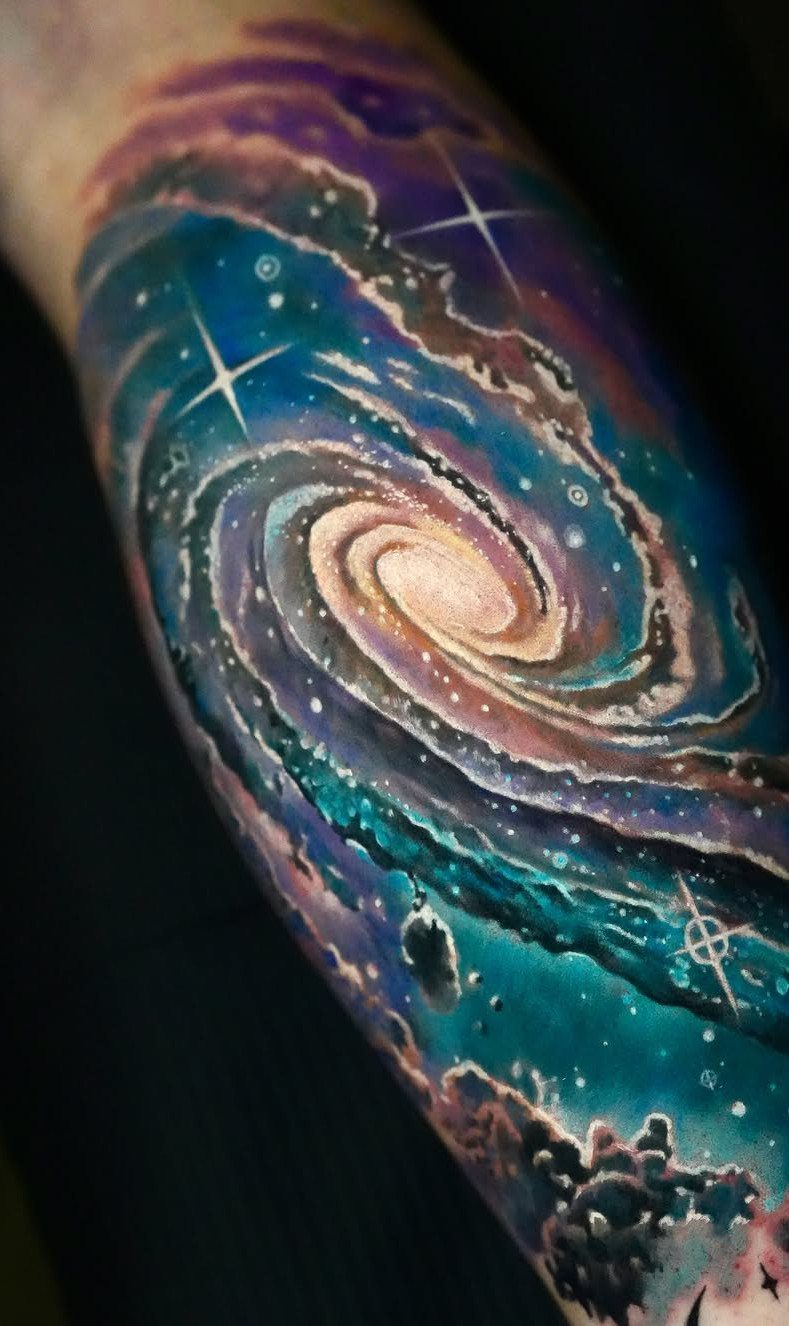 Universe Tattoo Pattern: 8 Space-Inspired Designs for Your Next Ink 2 A vibrant, colorful spiral galaxy tattoo with swirling blue and purple nebula patterns on skin.