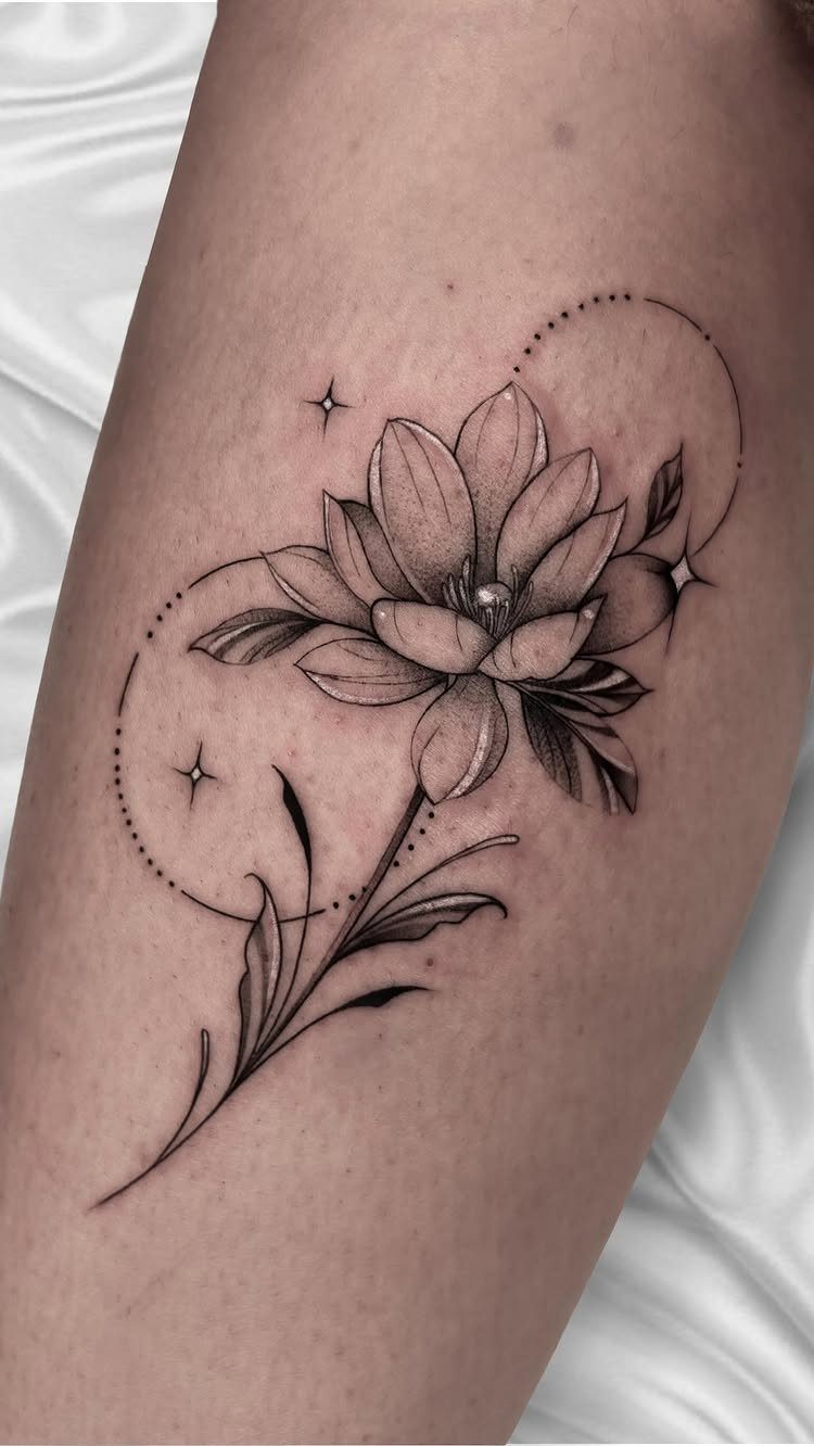 Fine line black ink water lily tattoo with delicate petals and dotted circular accents on skin.